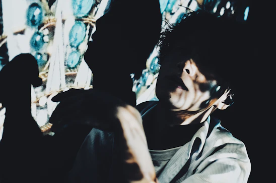 A shadowed portrait of zxoe bathed in electric blue light with glitch effects distorting the edges.
