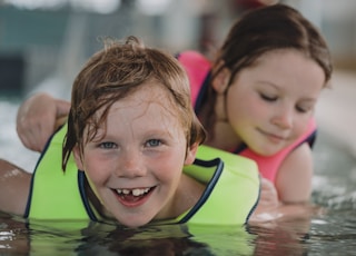 girl in pink tank top swimming on pool during daytime