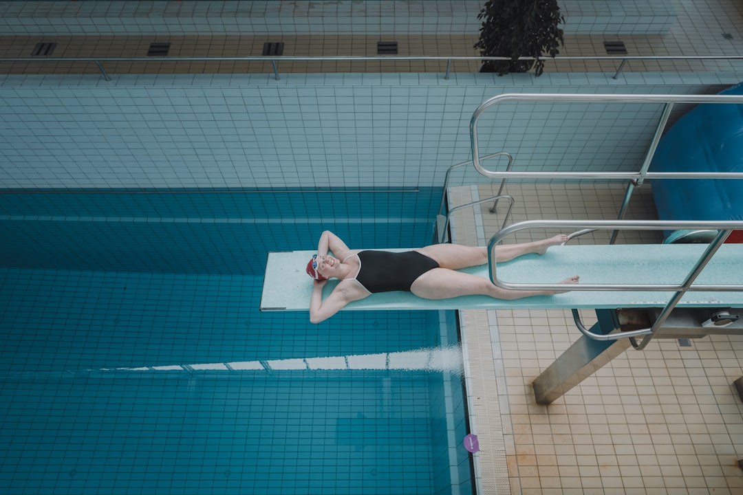 woman in black shorts standing beside swimming pool during daytime