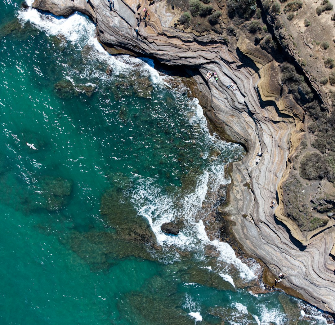 brown rock formation beside body of water during daytime