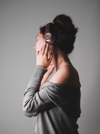 woman in gray long sleeve shirt covering her face with her hands