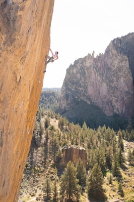 man in black jacket and black pants climbing mountain during daytime