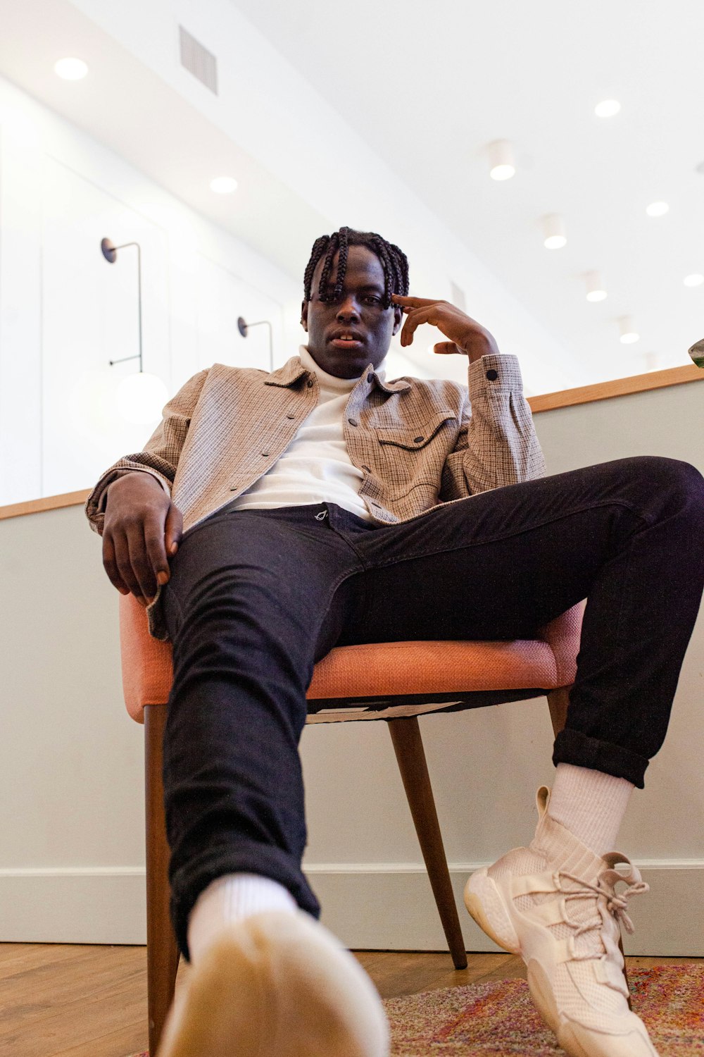 man in black pants and white sweater sitting on brown wooden chair