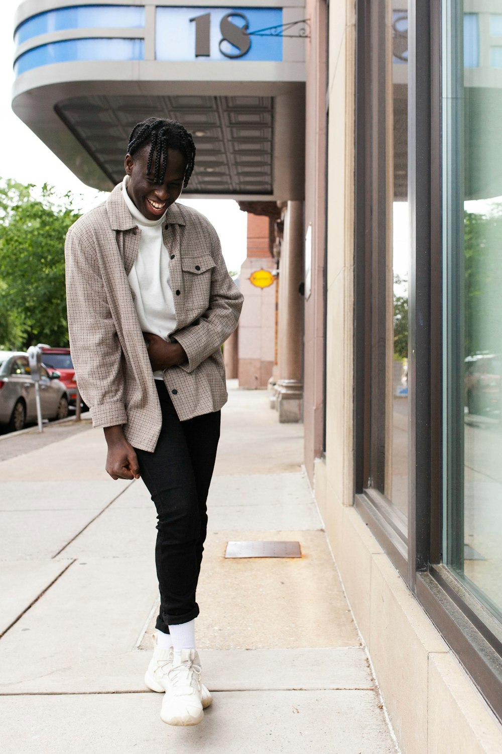 man in white sweater and black pants standing near glass window