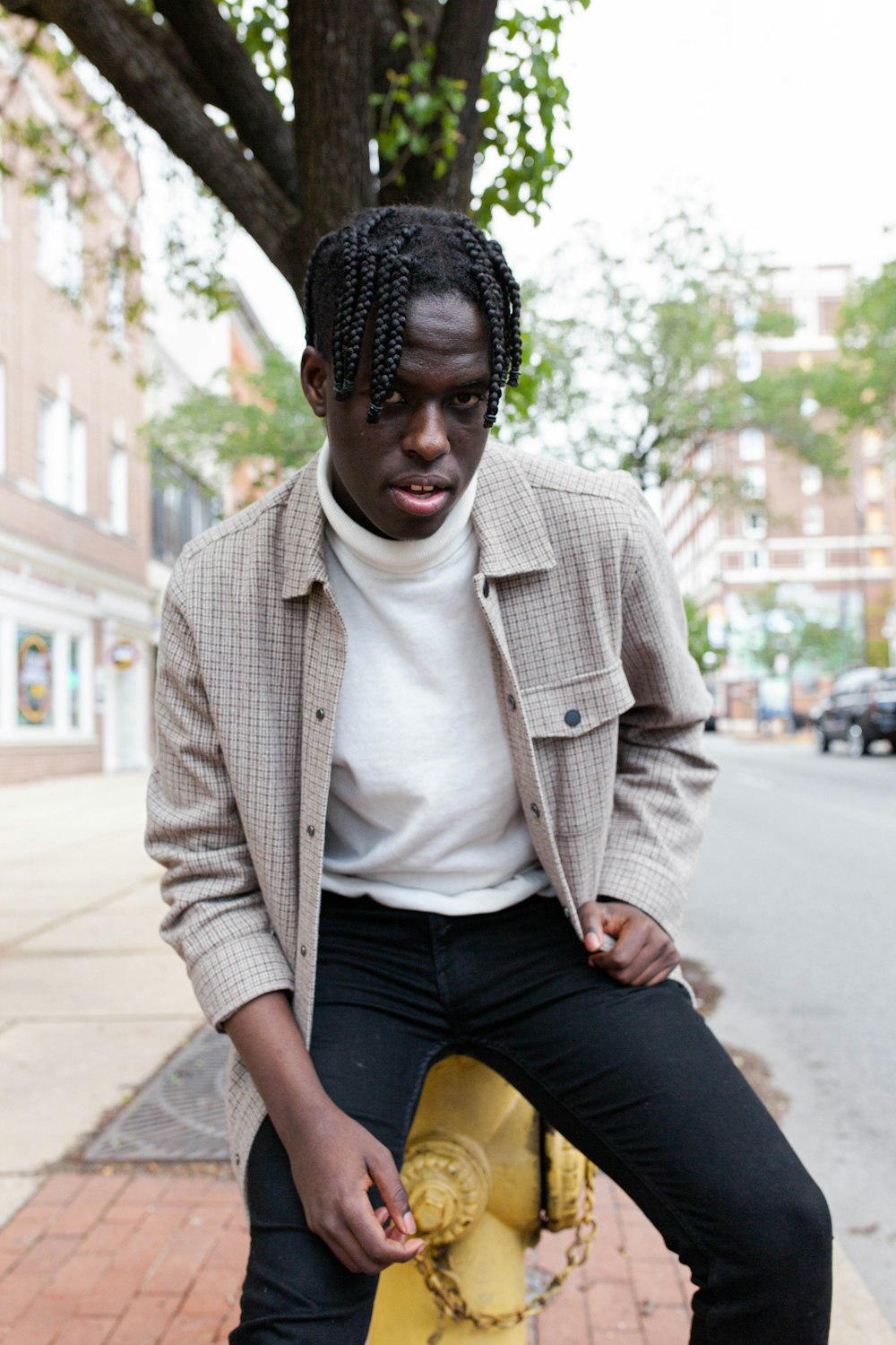 man in white button up shirt and blue denim jeans sitting on sidewalk during daytime