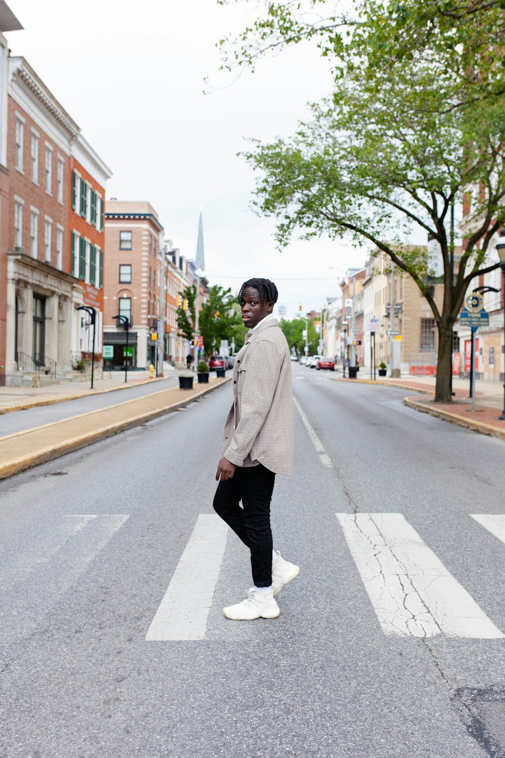 man in white coat standing on road during daytime