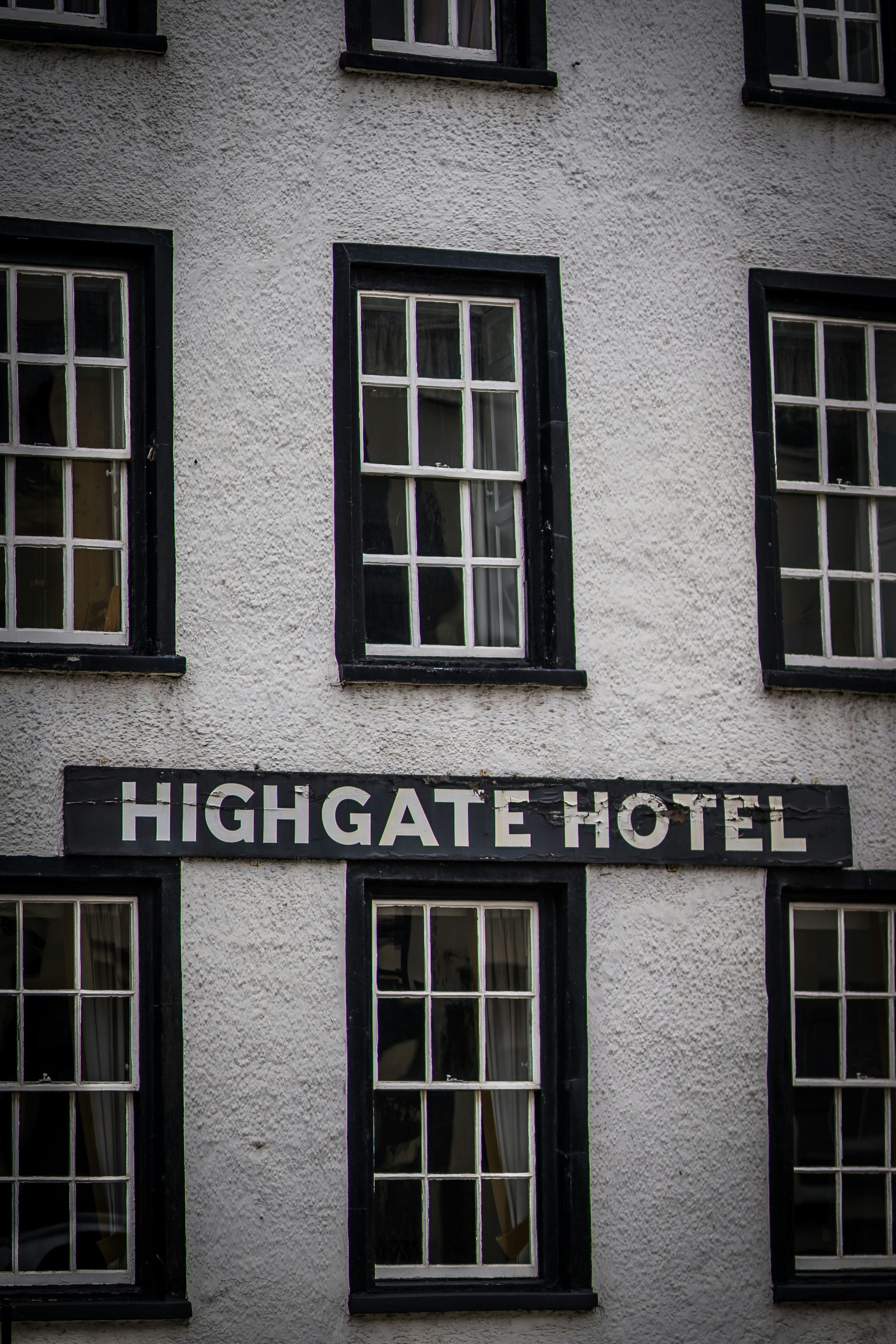 A white building with black windows and a sign that says highgate hotel ...