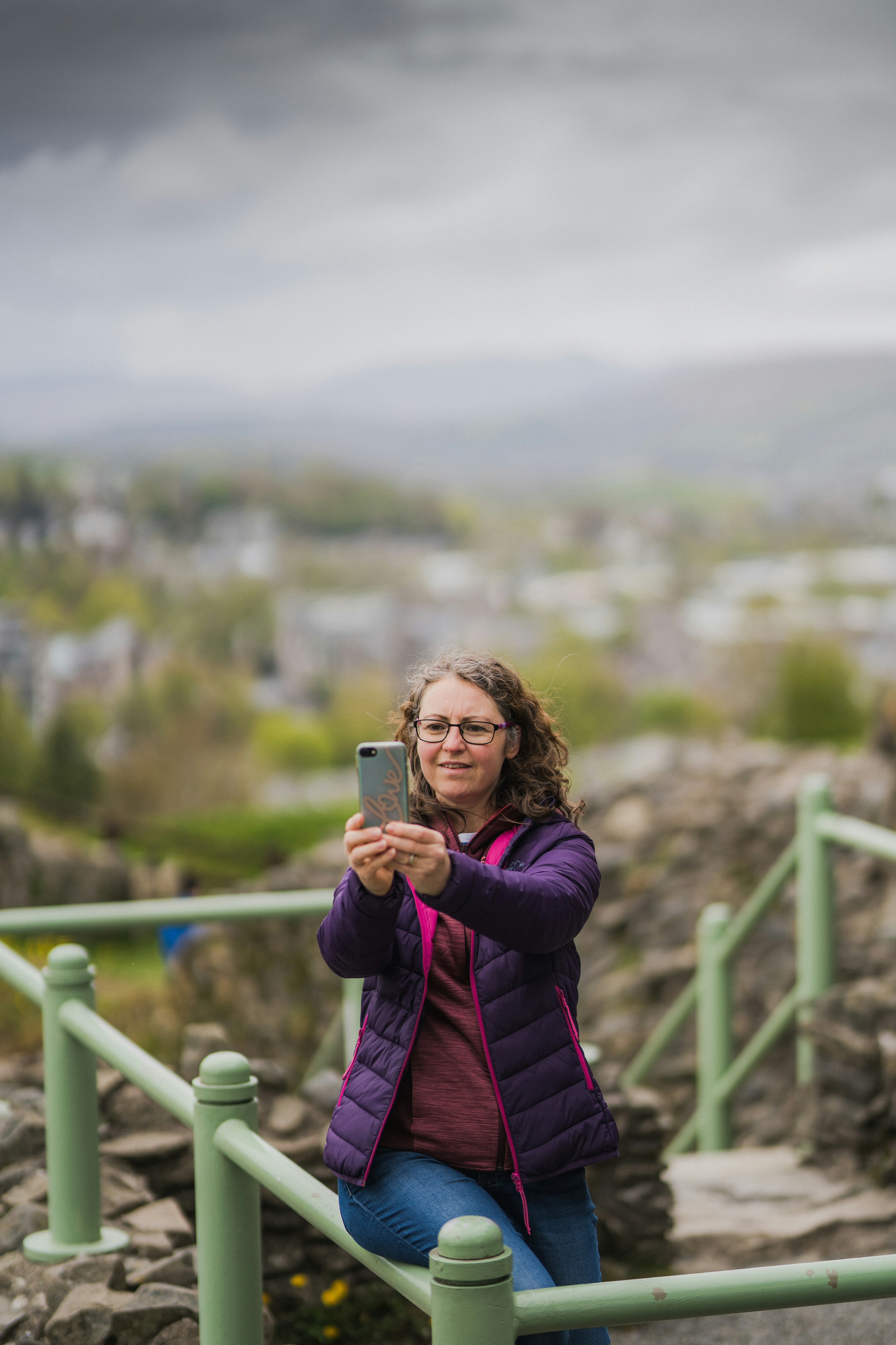 woman in purple jacket holding silver iphone 6