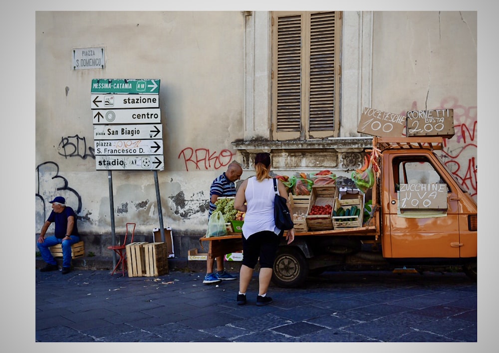 man and woman sitting on orange and white truck during daytime