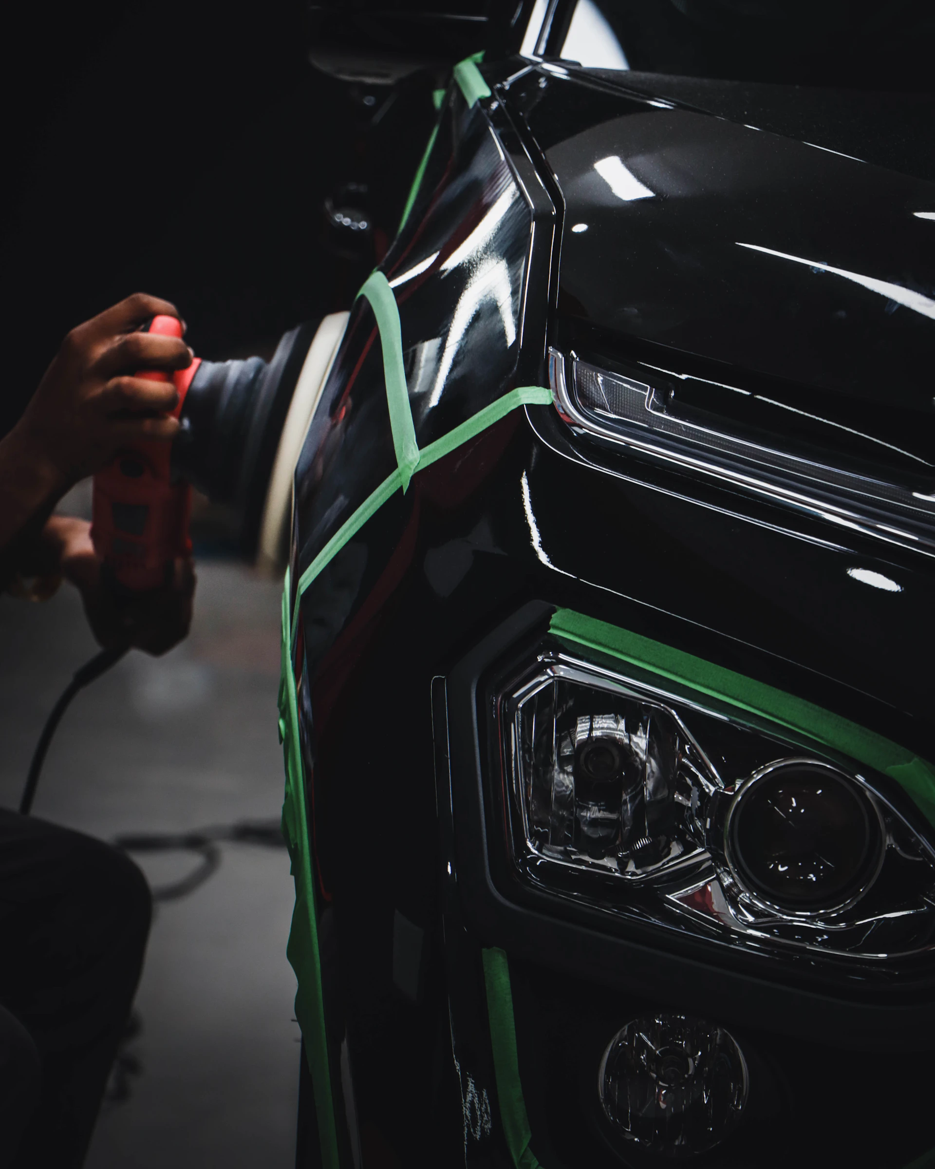 Detailing technician machine polishing dark car paint for gloss and protection preparation