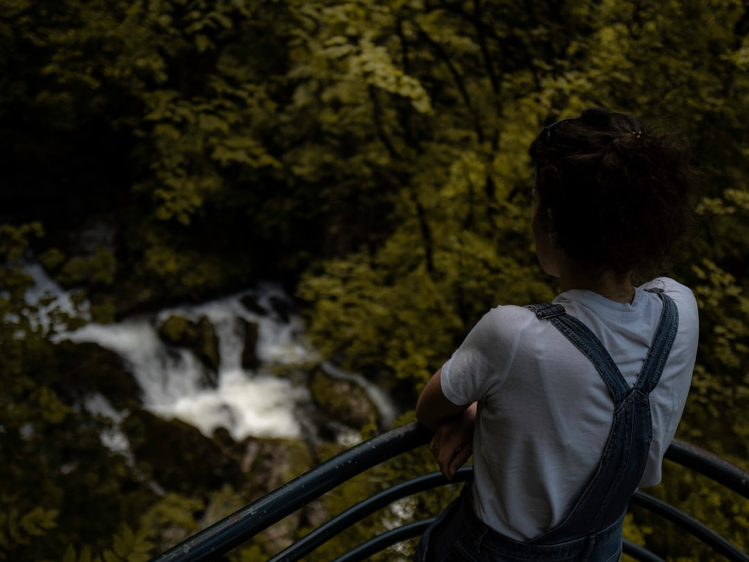 man in white shirt and blue backpack standing on bridge