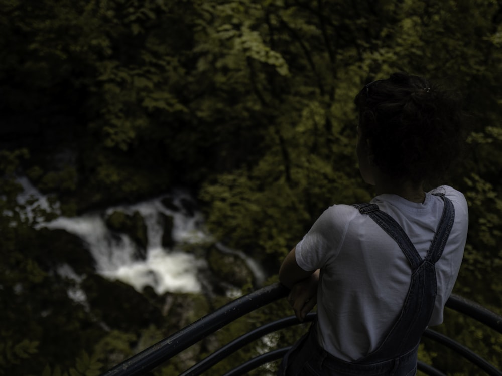 man in white shirt and blue backpack standing on bridge