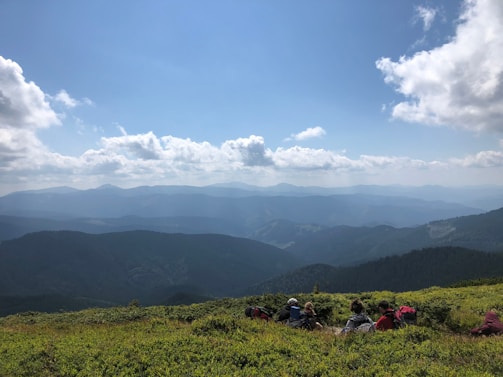 A vibrant group photo at a lush green valley with colorful backpacks and smiles.