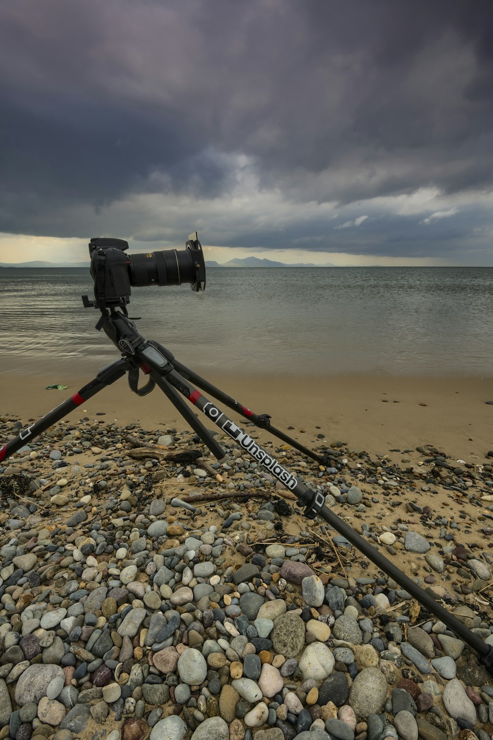 black camera on black tripod on brown sand near body of water during daytime