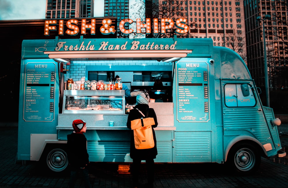 woman in brown coat standing in front of food stall