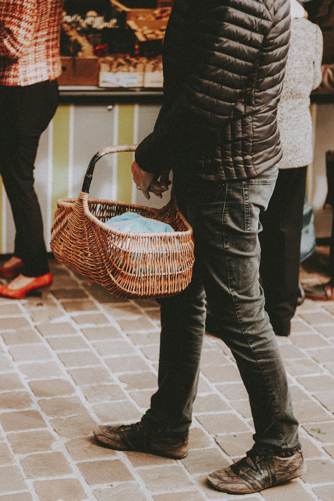 person in black and white long sleeve shirt and blue denim jeans holding brown woven basket