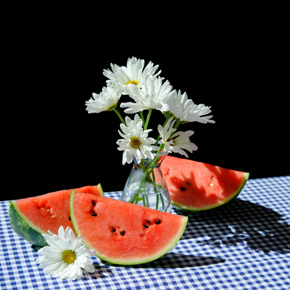 sliced watermelon beside white daisy flowers