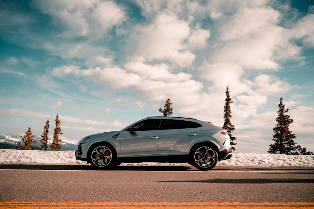 blue coupe on gray asphalt road under white clouds and blue sky during daytime