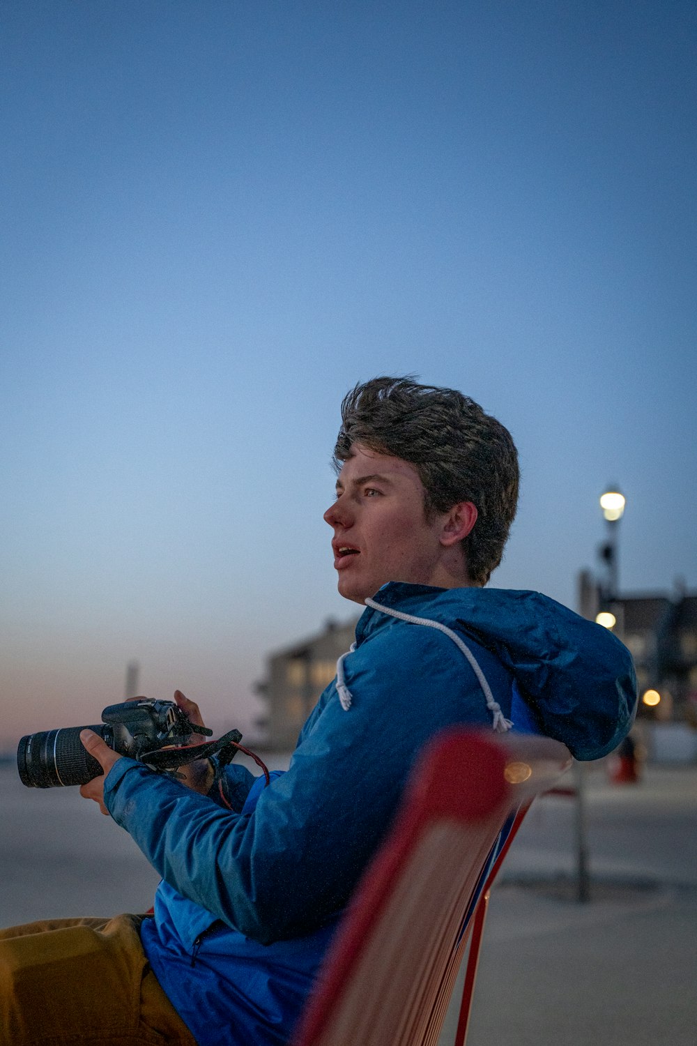 man in blue and red jacket holding black dslr camera during daytime