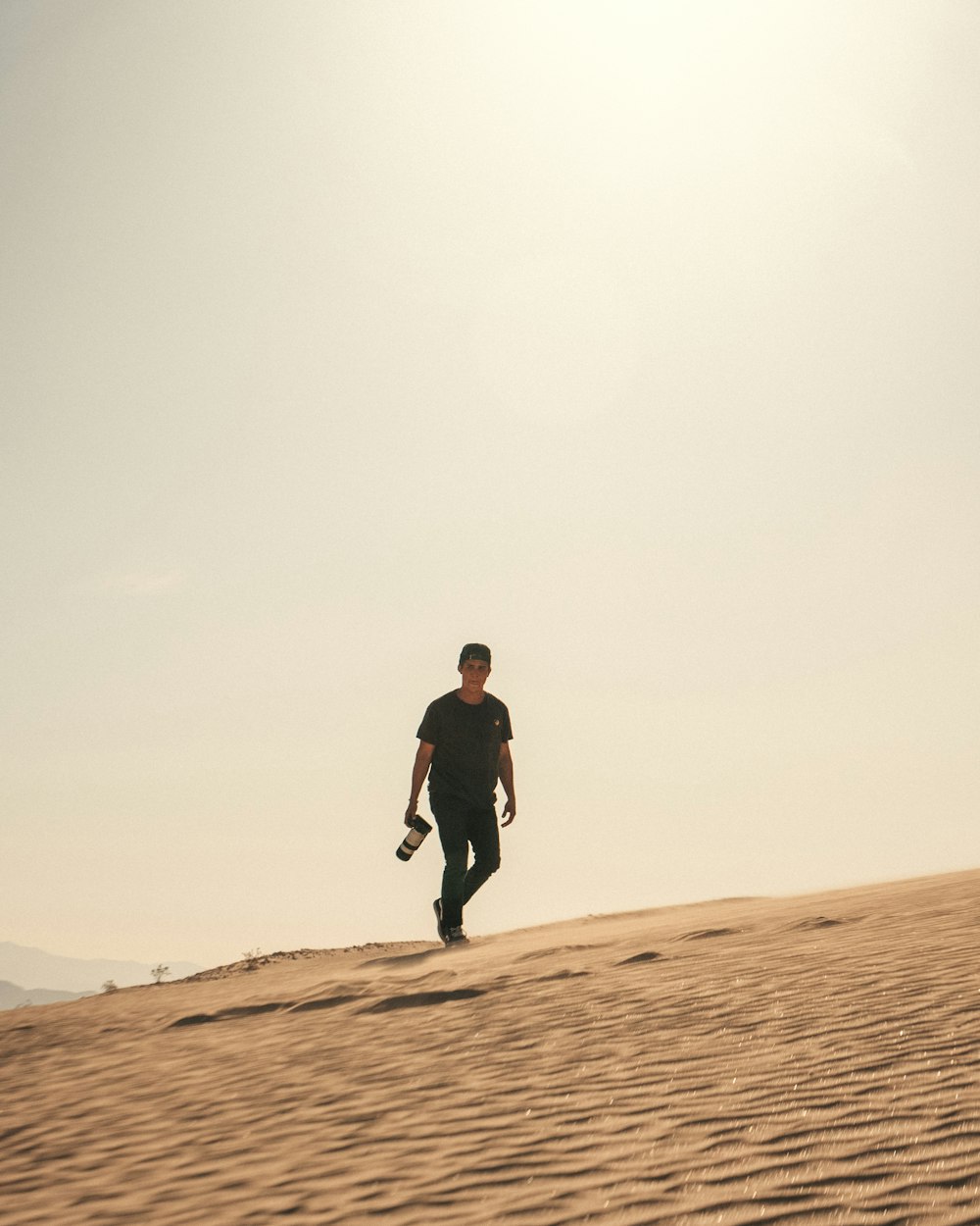 man in black jacket walking on brown sand during daytime