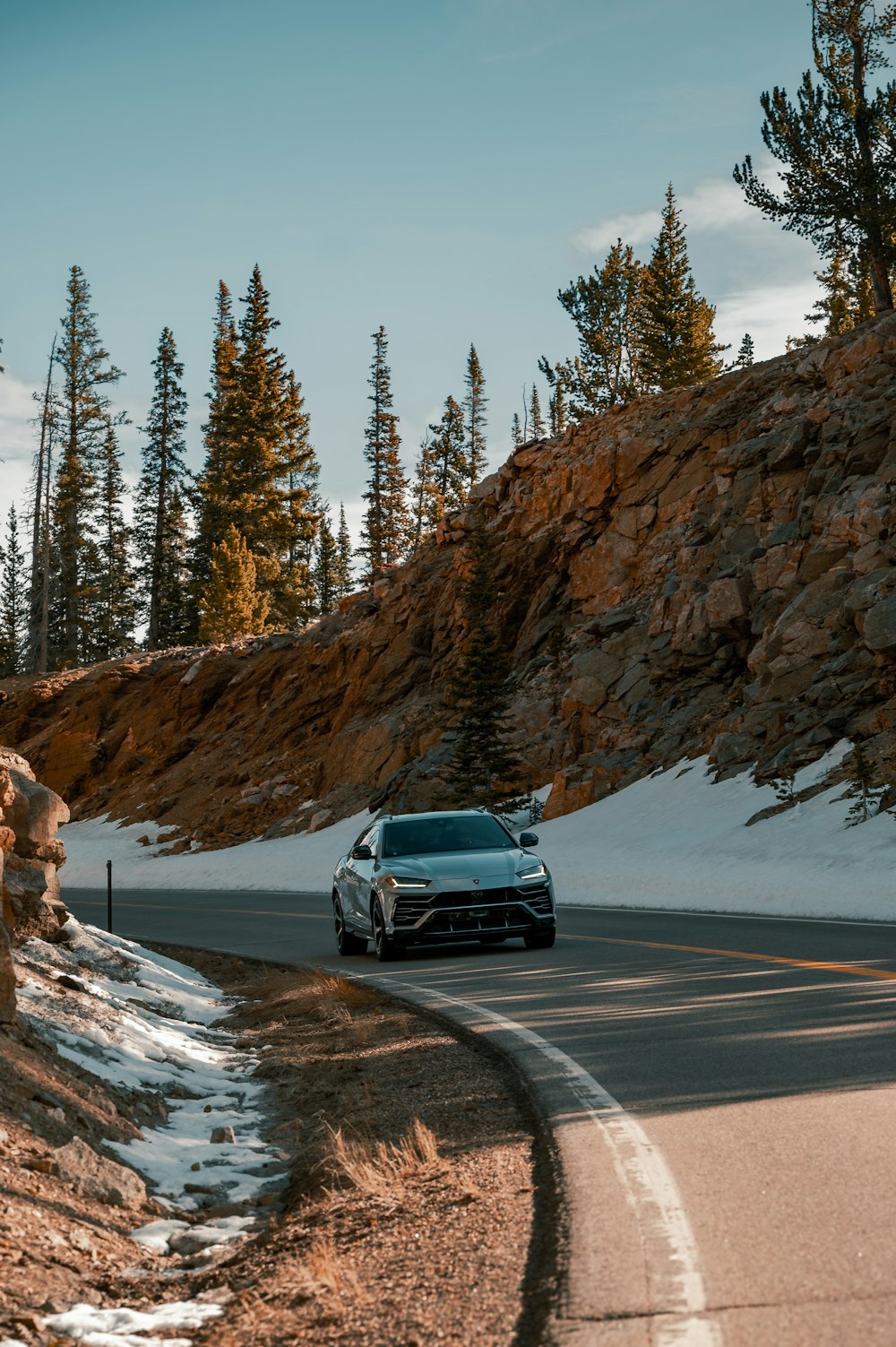 black car on road near brown rocky mountain during daytime