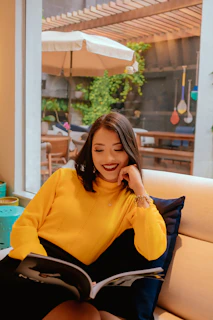 A relaxed living room scene featuring a woman in a cozy knit sweater and leggings, reading a fashion magazine.