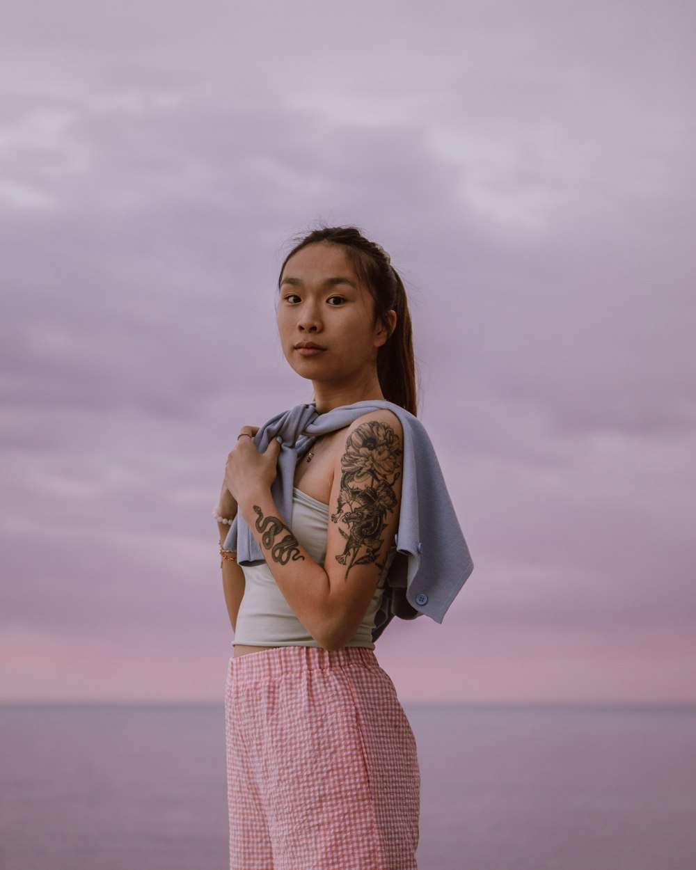 woman in pink and white plaid dress holding white and black backpack