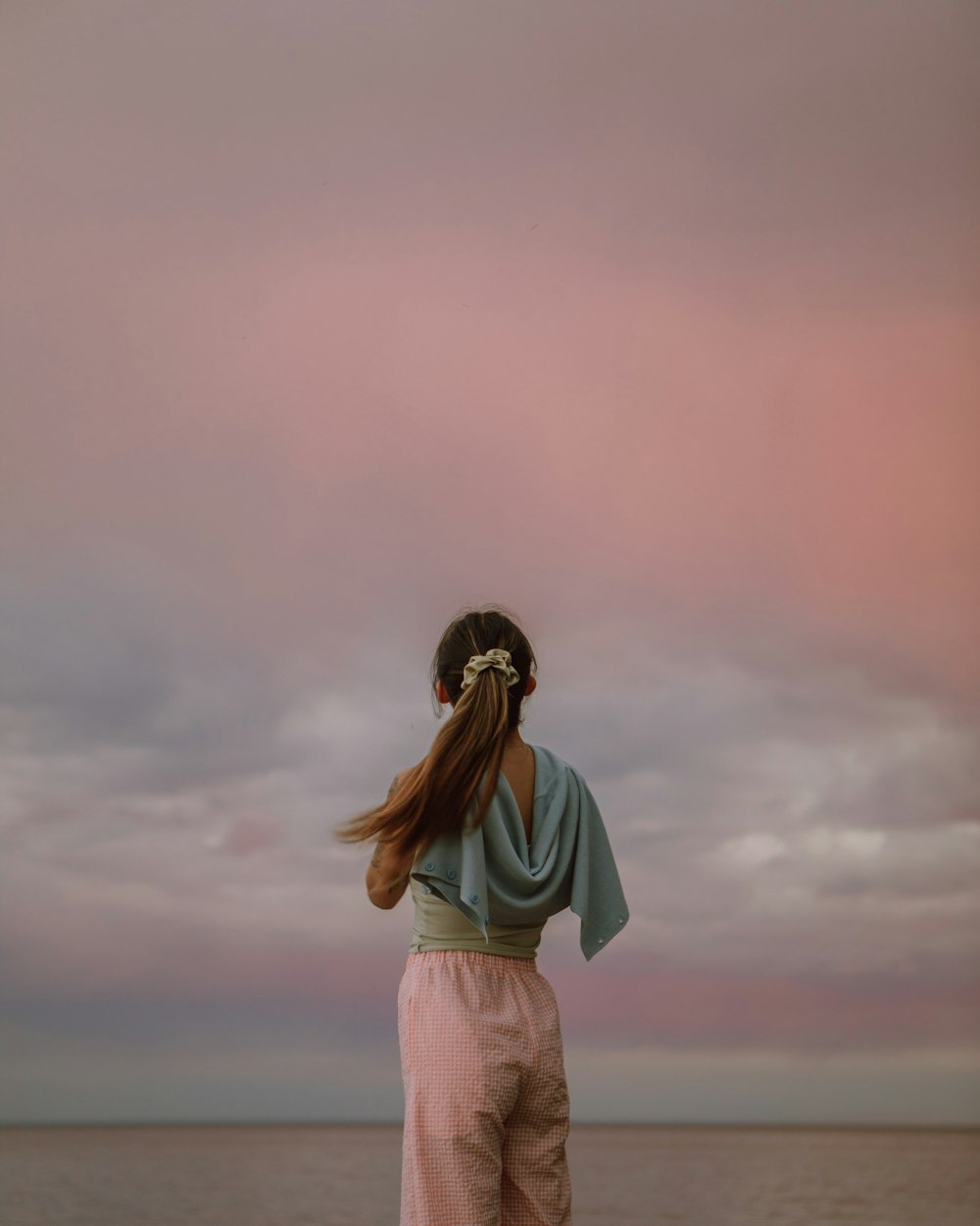 woman in white shirt and gray skirt standing under gray sky