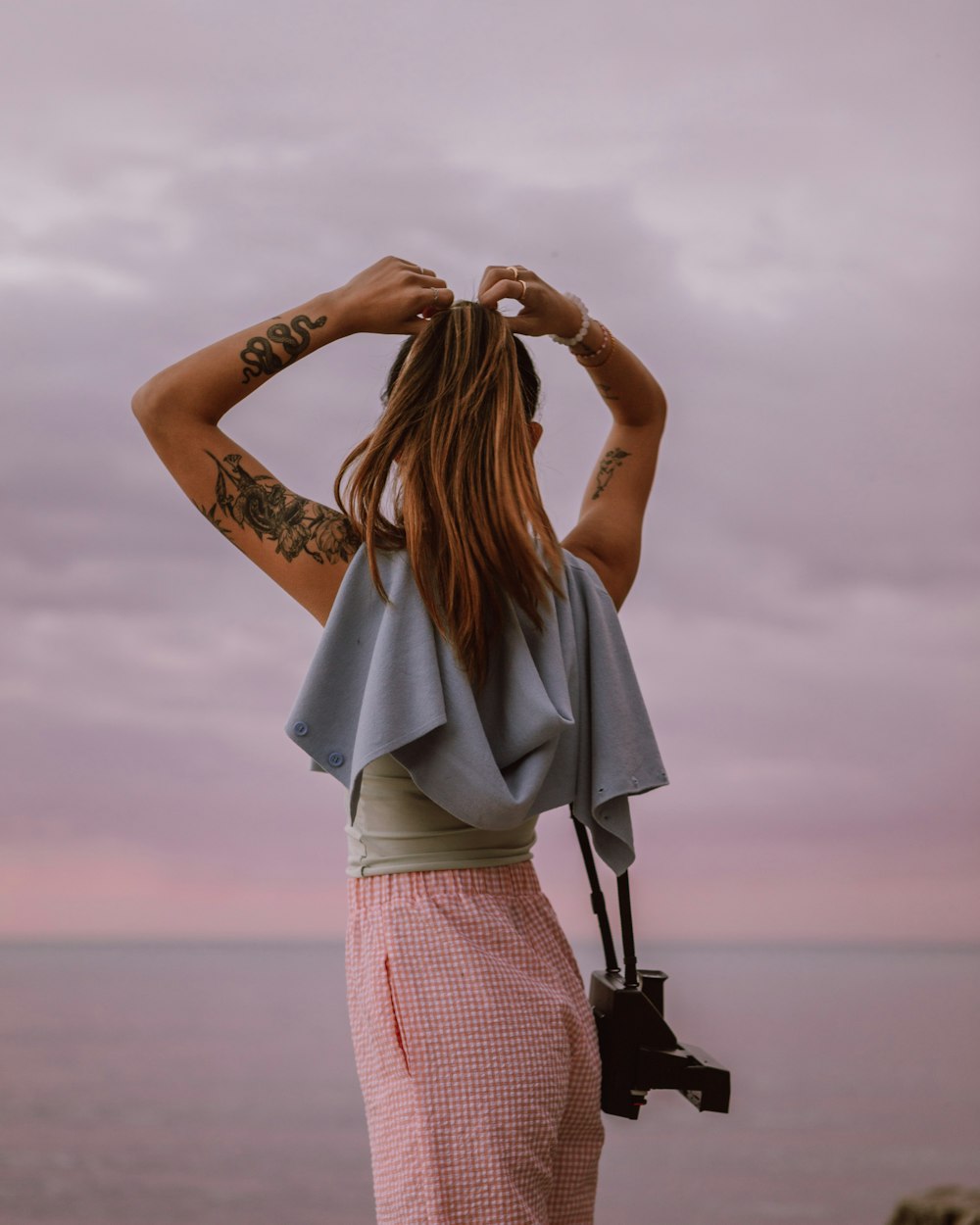 woman in pink and white plaid skirt holding her hair