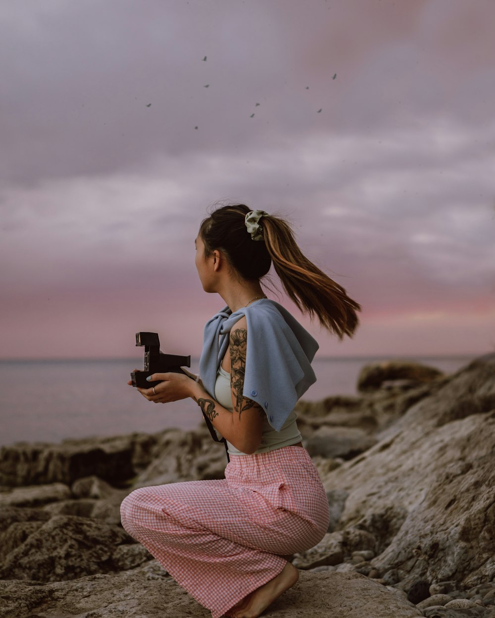 woman in white shirt and pink pants holding black smartphone