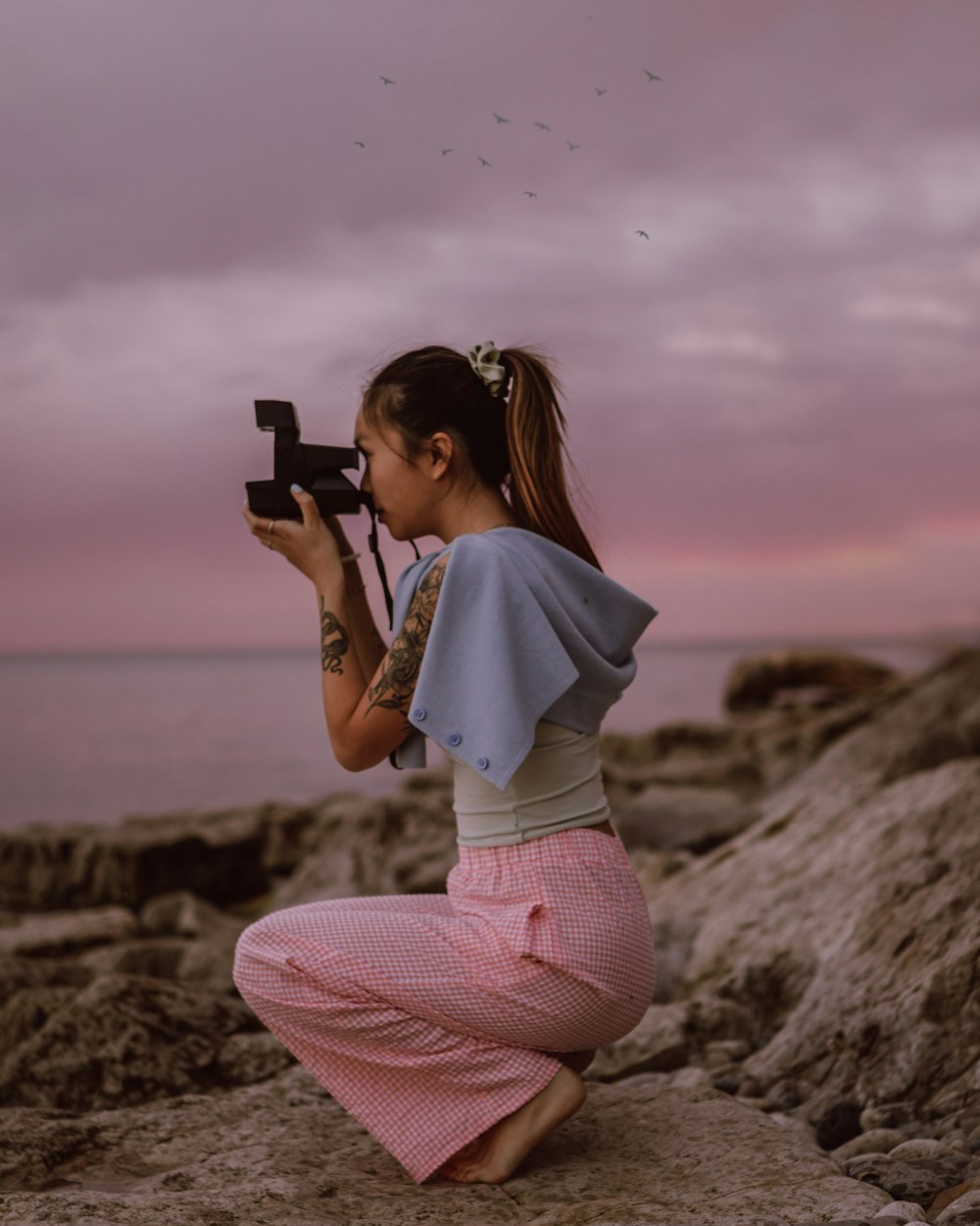 woman in white shirt and pink pants holding black smartphone