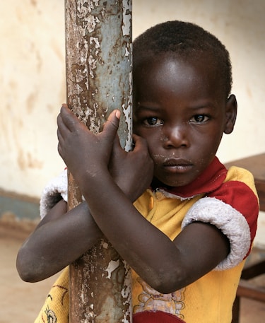 boy in yellow and red polo shirt holding brown wooden stick