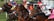 A group of jockeys riding racehorses are caught in mid-action, all wearing colorful racing silks and helmets. They appear to be at the starting gate, with focused and determined expressions as they begin a race. The background includes greenery and parts of the racing infrastructure.