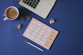 white and brown computer keyboard beside white ceramic mug on blue table
