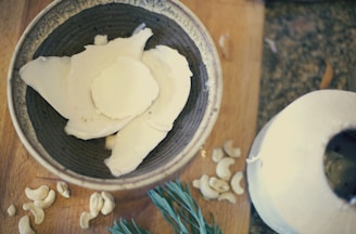Close-up of fresh coconut halves and raw spices on a wooden table with soft natural light.
