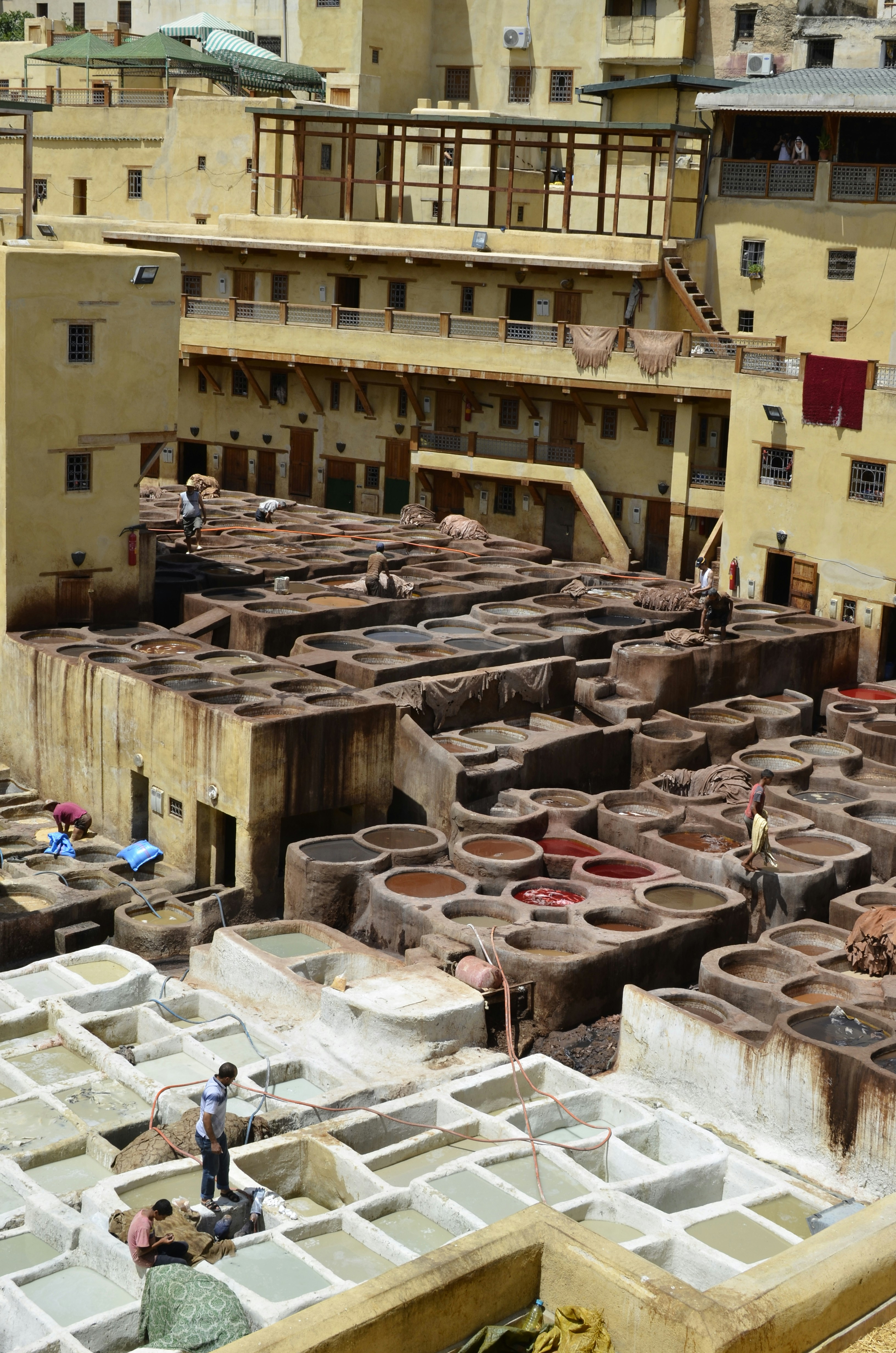 Fes ancient medina tanneries with colorful dye vats and leather workers in Morocco