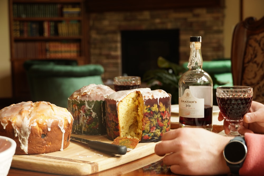 person holding bread with cheese and wine bottle