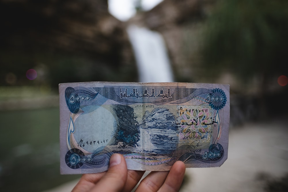 滝を背景に紙幣を持つ人