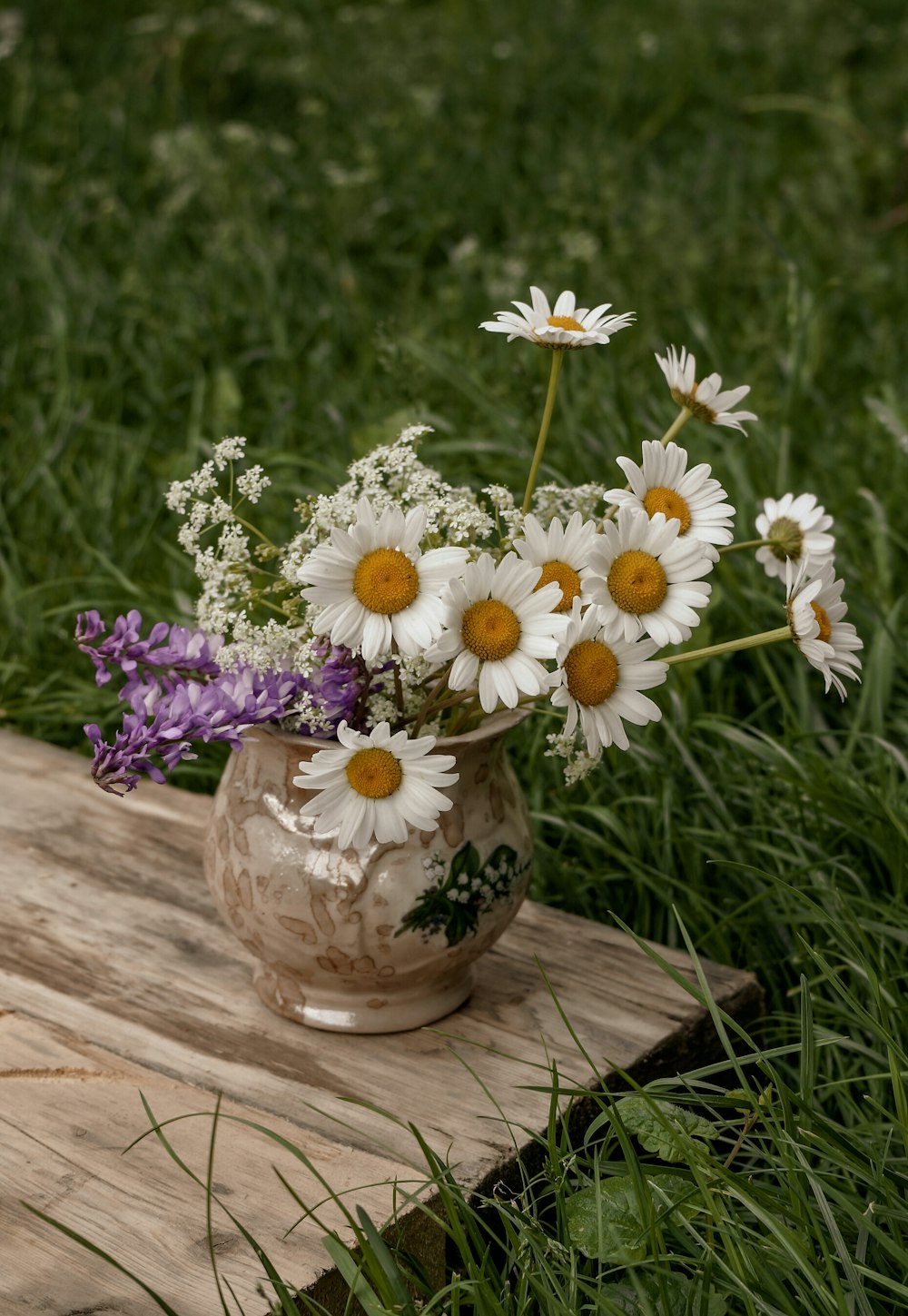 white and purple flowers in brown ceramic vase