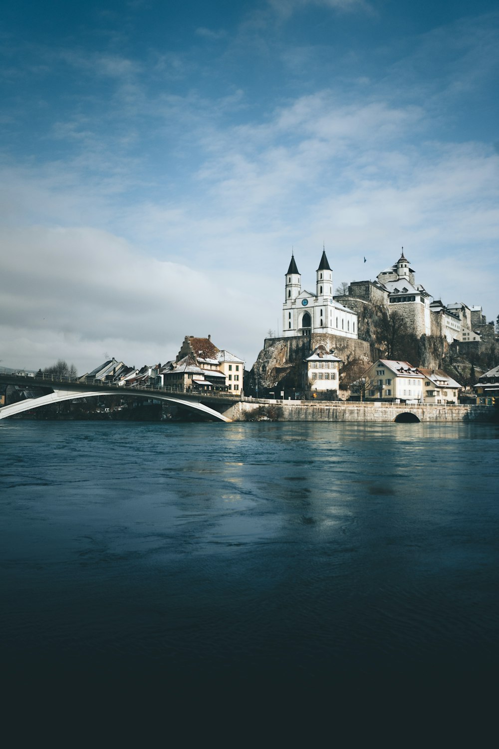 white and gray concrete building beside river under blue sky during daytime