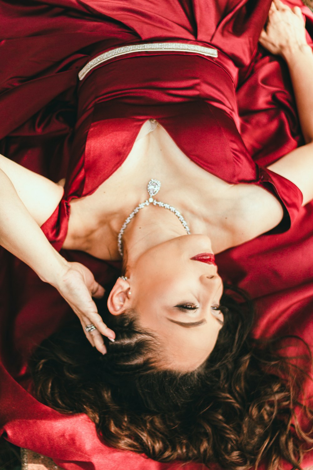 woman in red dress lying on red textile