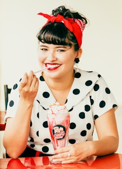 woman in white and black polka dot shirt holding red and white plastic cup