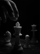 grayscale photo of person holding chess piece