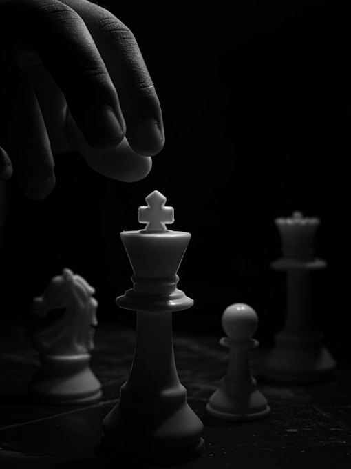 grayscale photo of person holding chess piece