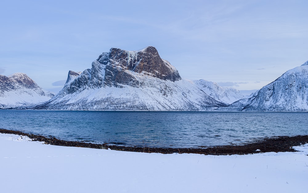 snow covered mountain near body of water during daytime