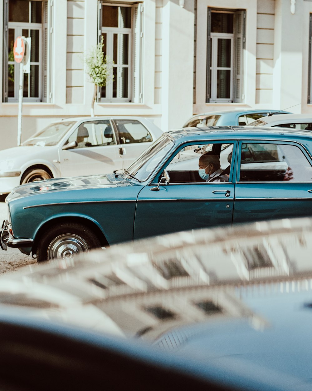 blue car parked near white building during daytime