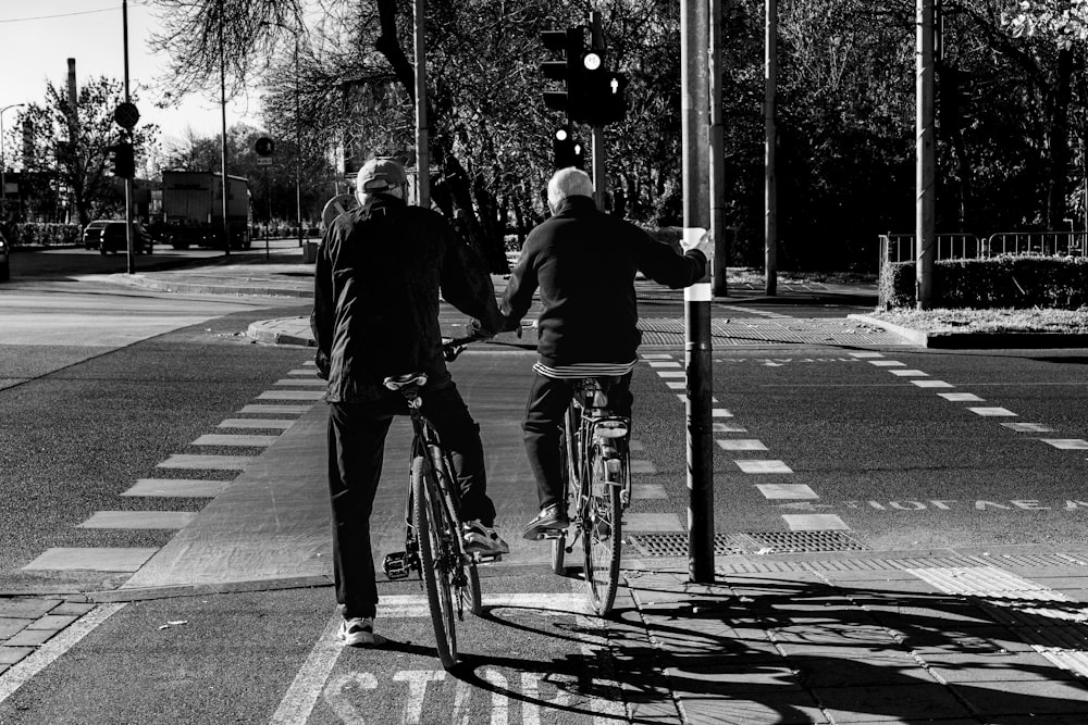grayscale photo of people riding bicycle on road
