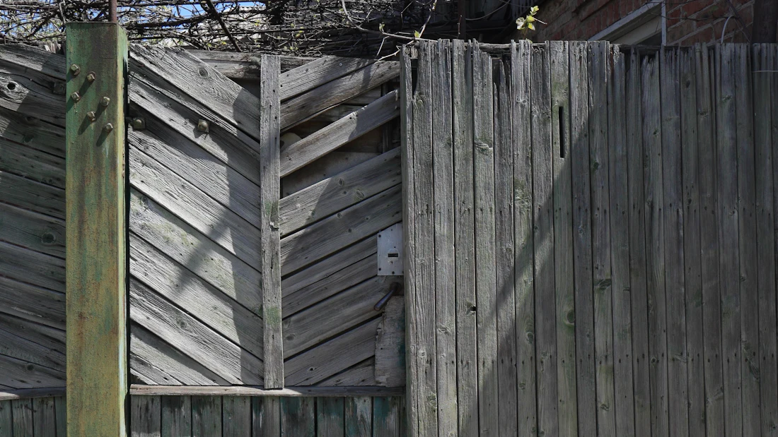 Weathered gray fence boards, some set at an angle