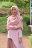 A woman wearing a flowing abaya, standing gracefully in a sunlit garden.