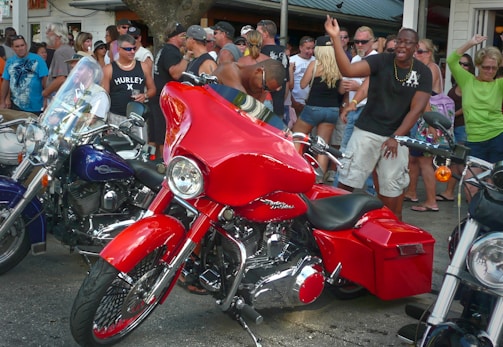 Shot of a spirited crowd at an outdoor event, riders chatting beside classic bikes.